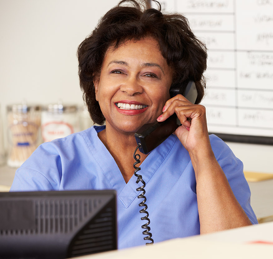 A nurse on the phone smiling as she provides customer service